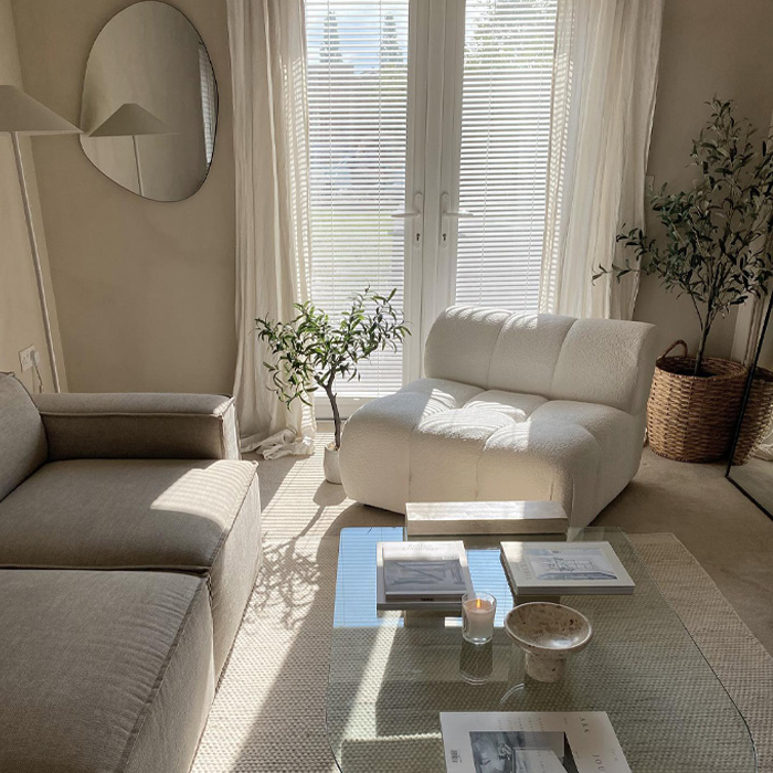 White living room with grey couch and white chair next to a glass coffee table 