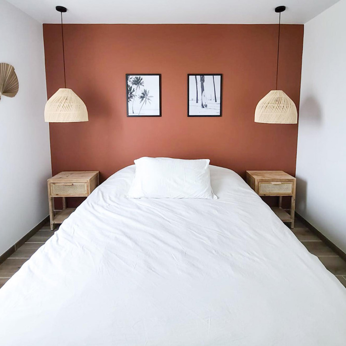 A bedroom with terracotta and white bed 