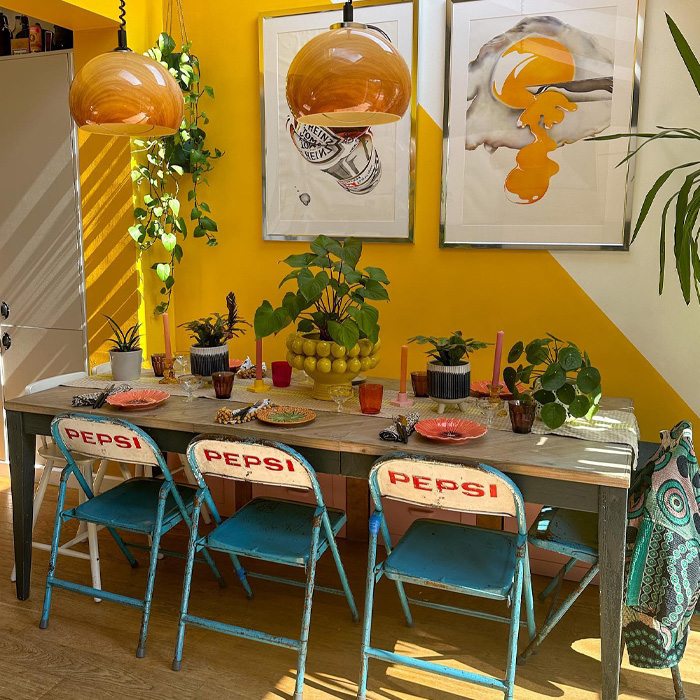 Yellow dining room showcasing warm colors with blue Pepsi chairs, a grey table, and vibrant decor accents. Yellow dining room showcasing warm colors with blue Pepsi chairs, a grey table, and vibrant decor accents.