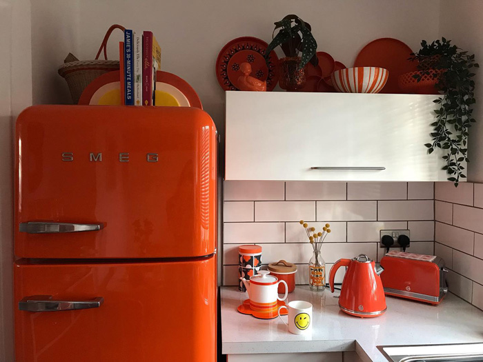 Orange fridge and kitchen appliances in a white kitchen showcasing warm colors for vibrant decor ideas. Orange fridge and kitchen appliances in a white kitchen showcasing warm colors for vibrant decor ideas.