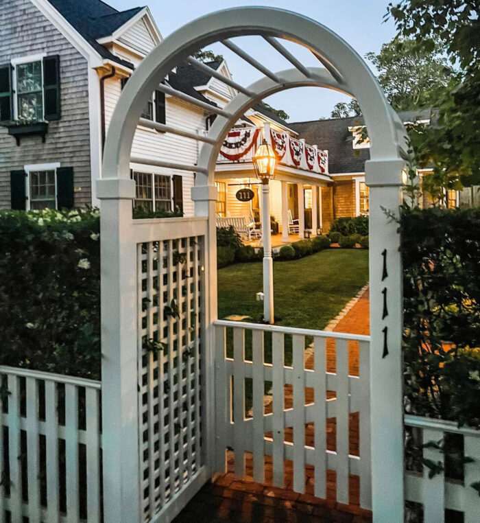 white picket fence with a rounded arch in front of a house