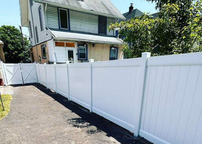 Tall vinyl white picket fence in front of a two-story house