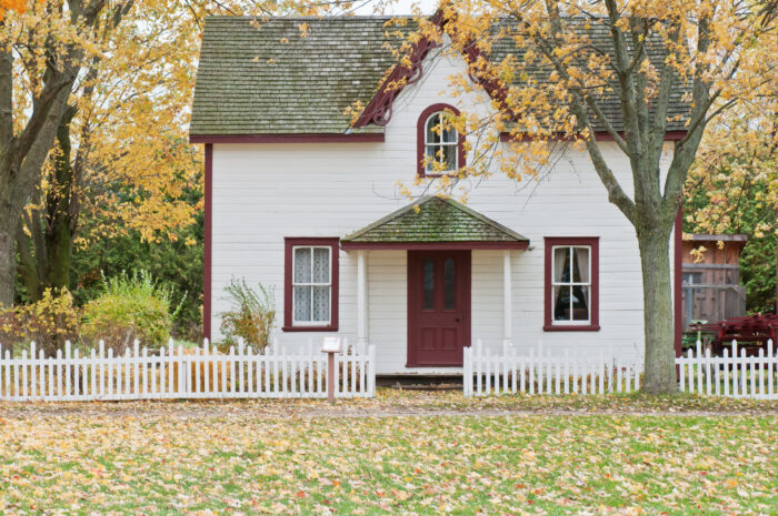 White and red wooden house with a short white fence outside