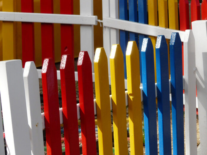 A picket fence with white, red, yellow, and blue panels