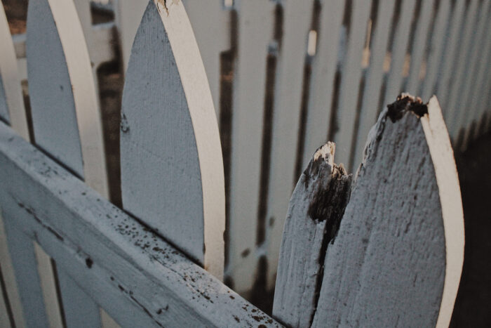 Damaged white wooden picket fence 