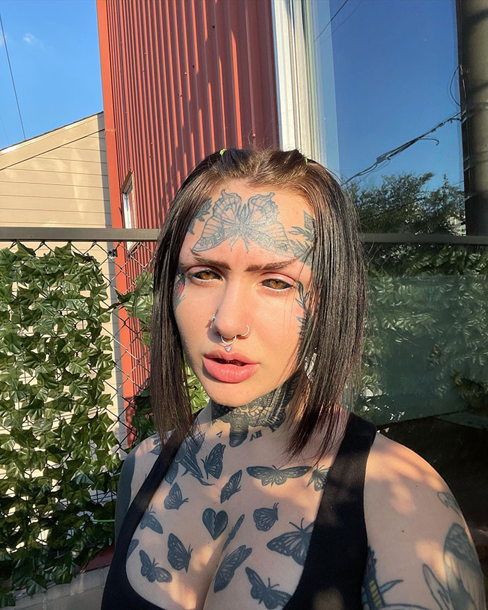 Woman with extensive tattoos outdoors, showcasing her inked look. Woman with extensive tattoos outdoors, showcasing her inked look.