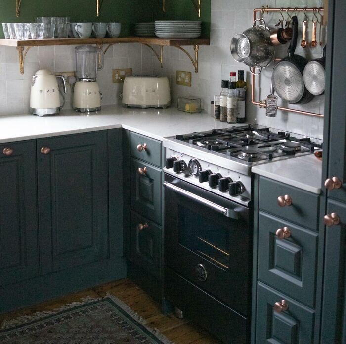 Green kitchen with dark green cabinets and wooden shelves