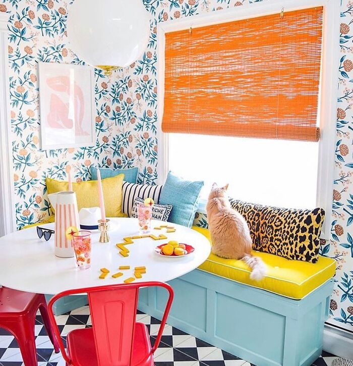 Room with patterned wallpaper white table with red chairs
