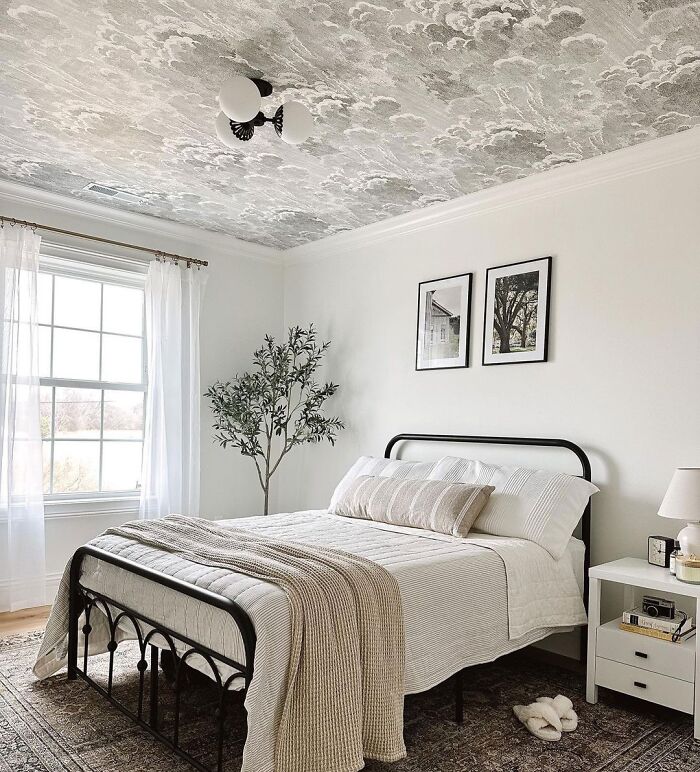 White room with wallpaper ceiling and bed with gray sheets