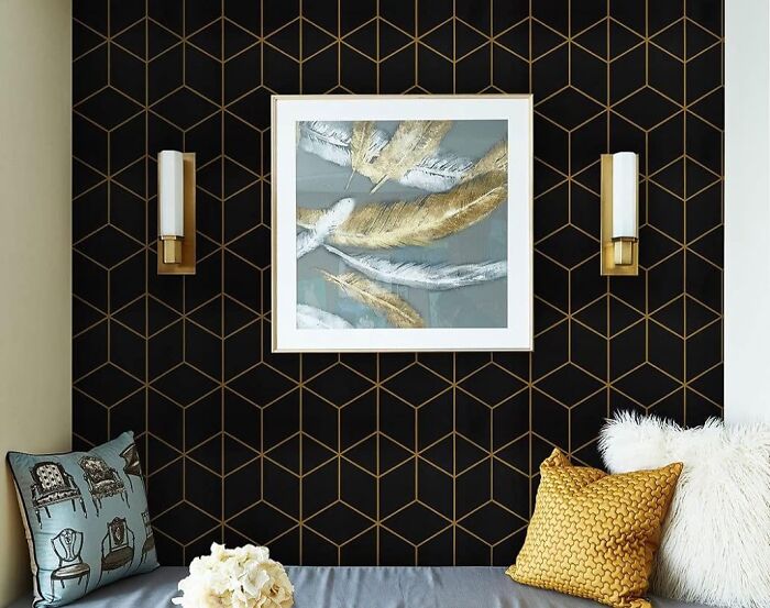 Room with gold and black geometric wallpaper painting and pillows