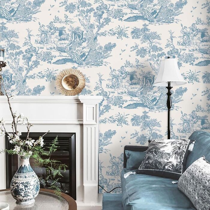 Room with blue vintage style wallpapers and blue sofa near fireplace