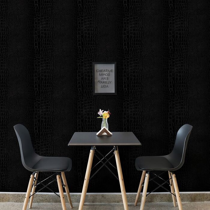 Room with dark crocodile skin wallpaper and black table with chairs