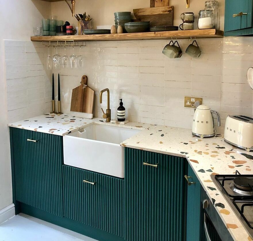 Green fluted kitchen cabinets and wooden shelves with kitchen items