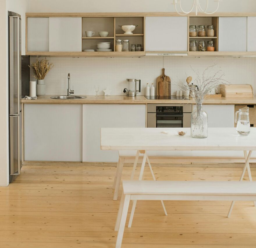 Dining table with a vase near the kitchen cabinets in wooden and white colors