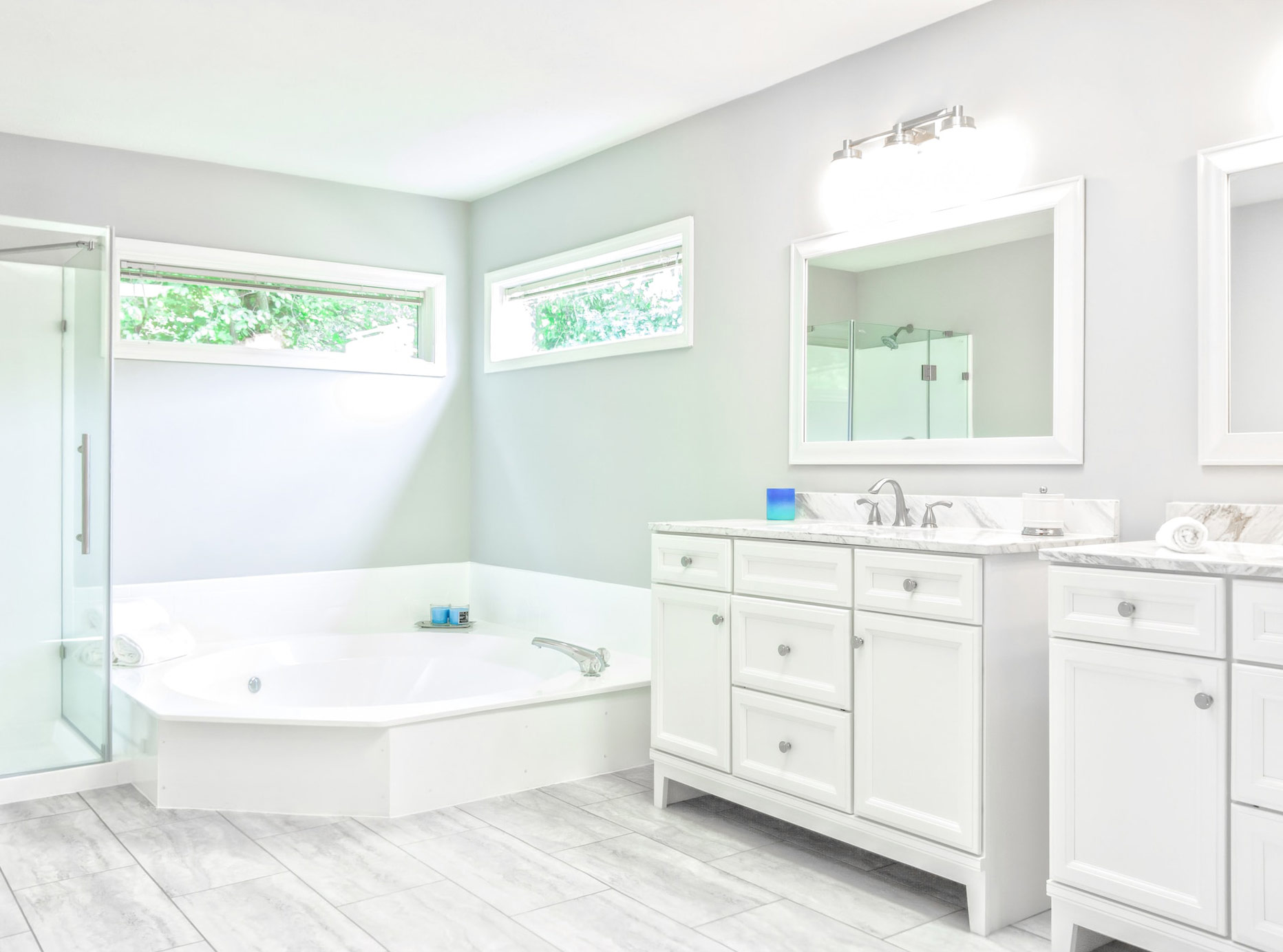 Light bathroom with horizontal narrow windows, mirrors, and white cabinets