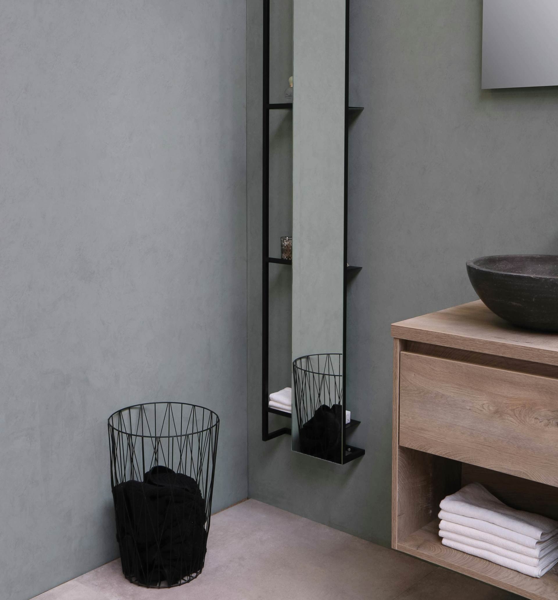 Gray bathroom with wooden cabinet, long, narrow vertical mirror, and black metal basket