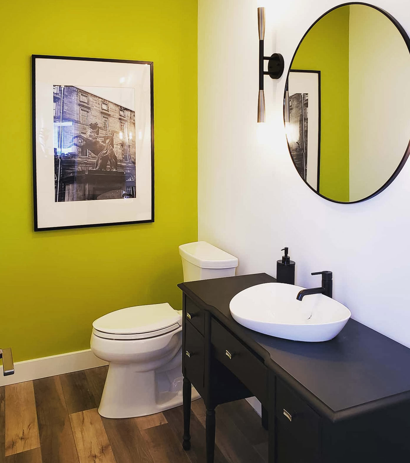 Bathroom with chartreuse color wall, round mirror and wall art