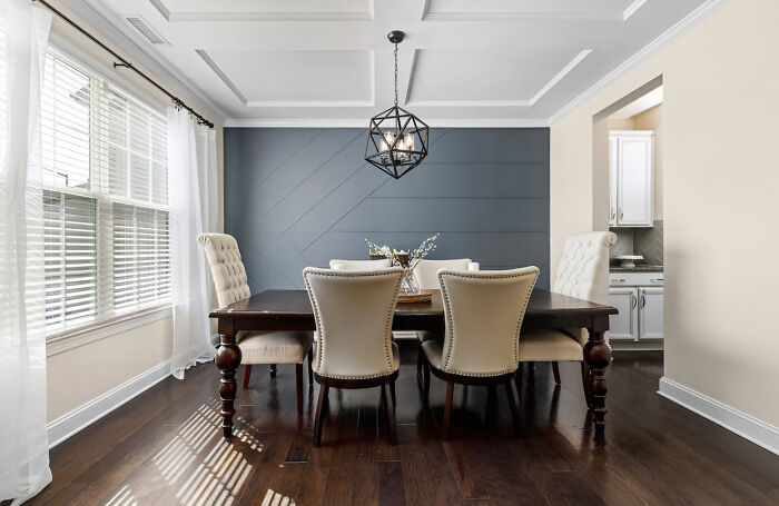 Dining room with a gray accent wall and white wainscoting ceilings