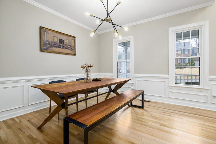 Dining room with wainscoting, wooden table, and a painting on wall