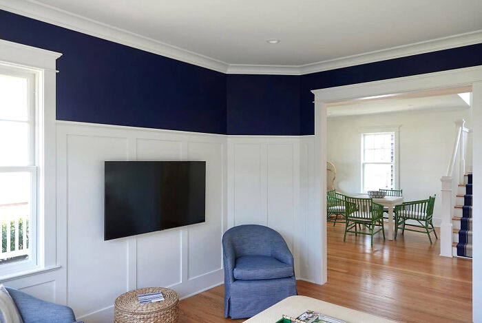 Beach house living room with dark navy color walls and white wainscoting