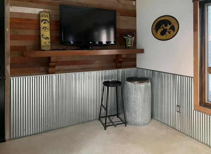 Room with metal wainscoting, reclaimed flooring on the walls and TV