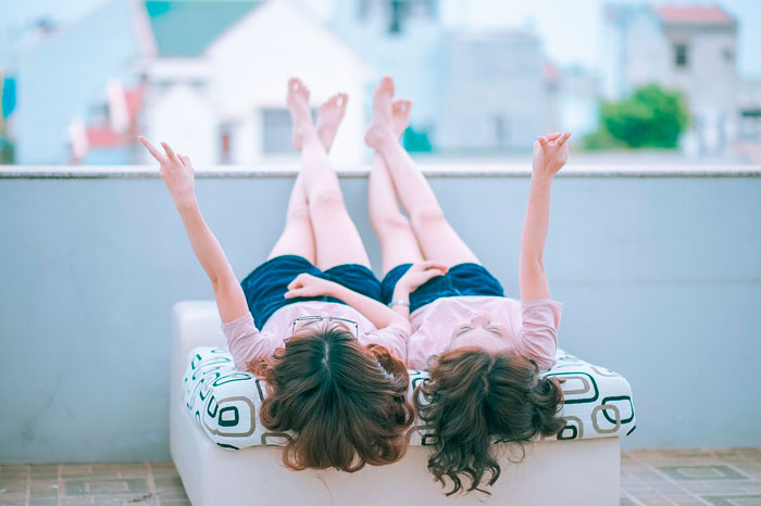 Two girls laying on top of a house roof 