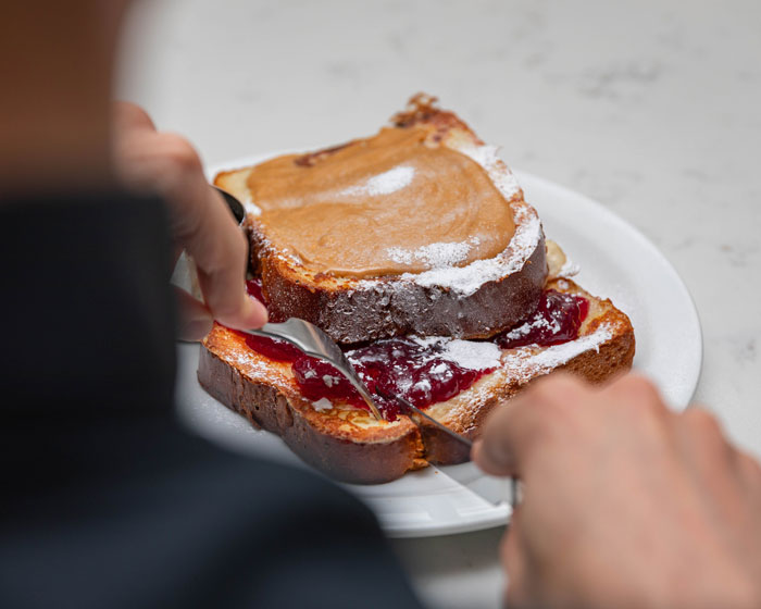 Person eating Peanut butter and jelly toast with knife and fork 
