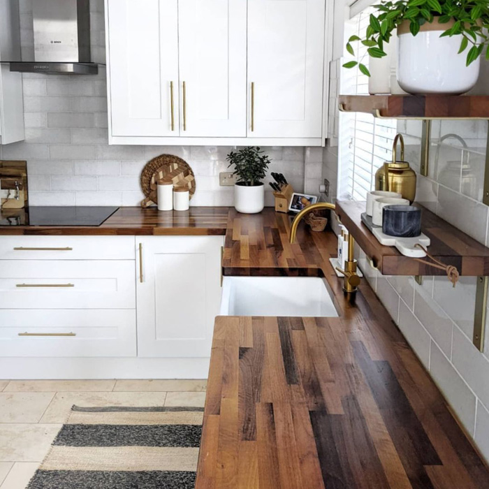Kitchen with white cabinets featuring shiny butcher block countertops and gold hardware for a classic and durable look Kitchen with white cabinets featuring shiny butcher block countertops and gold hardware for a classic and durable look