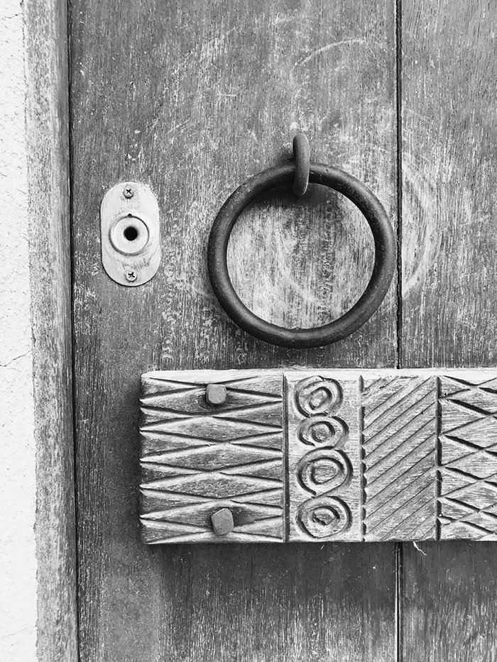 decorated woden panel and brass door knocker on a old doo