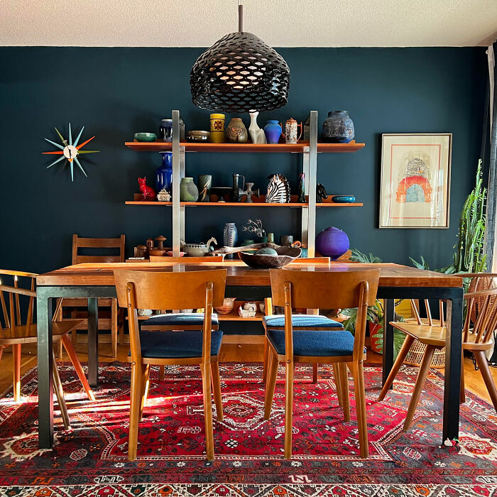 Dining room with dark blue walls, open shelves, wooden table and chairs, showcasing inspiring dining room ideas for family gatherings.
