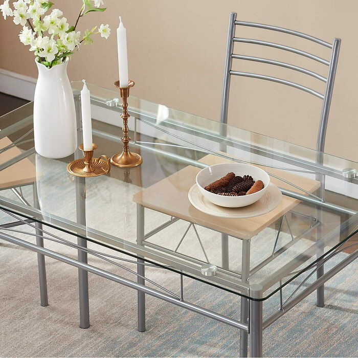 Modern dining room with glass table and metal chair featuring elegant decor for family gatherings and parties.