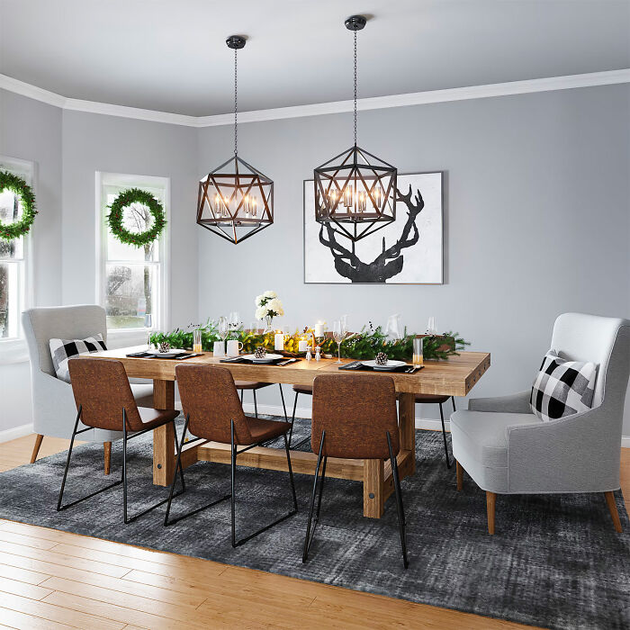 Gray dining room with wooden table and mixed chairs, decorated with greenery and modern pendant lights for family gatherings.