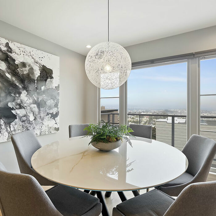 Gray dining room with marble table and gray chairs featuring modern design and large windows for natural light