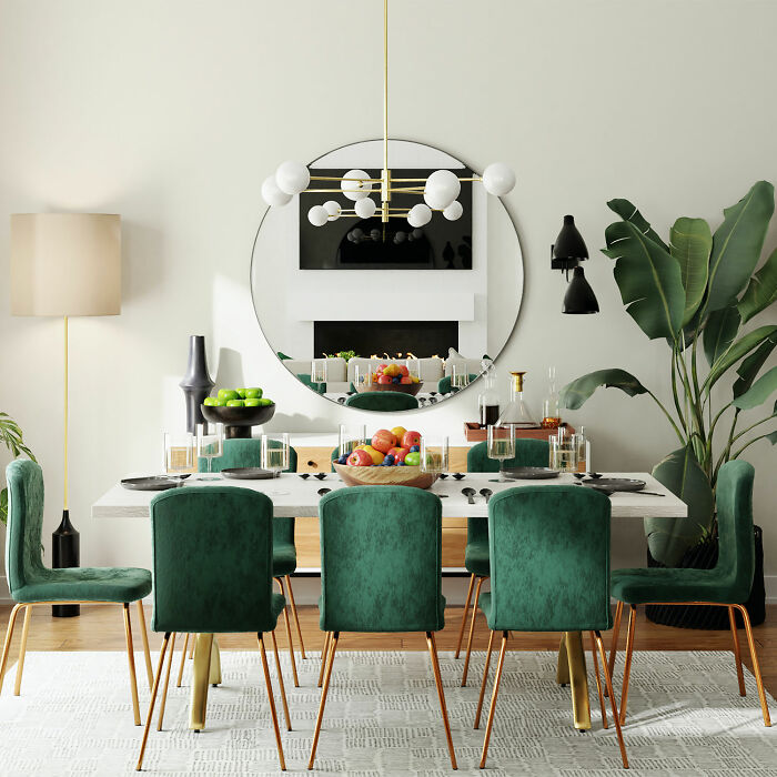 Dining room with a large round mirror, white table, and green velvet chairs enhancing family gatherings ambiance.