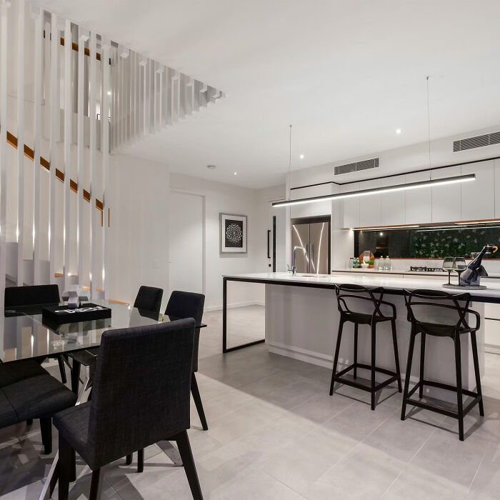 Modern dining room ideas featuring a white space with a glass table and black chairs for stylish family gatherings.