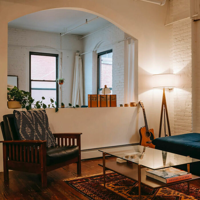 Dining room with arched wall, glass table, wooden chair, and warm lighting, showcasing inspiring dining room ideas.