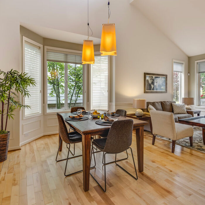 Dining room with a wooden table and gray chairs, featuring natural light and modern decor for family gatherings.