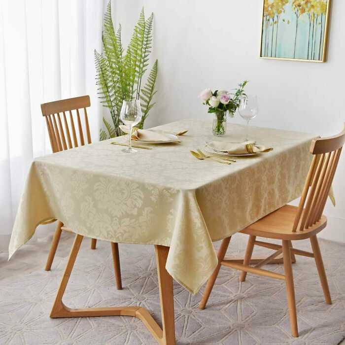 Dining room with wooden chairs, decorative tablecloth, flower centerpiece, and elegant table setting for family gatherings.