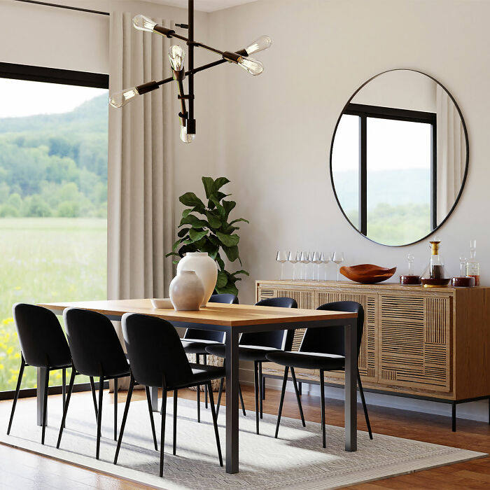 Dining room with black chairs, wooden table, large round mirror, and modern lighting enhancing family gatherings decor.