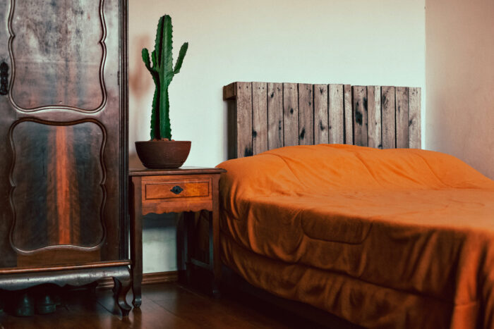 Orange cover on the bed with headboard made of pallets