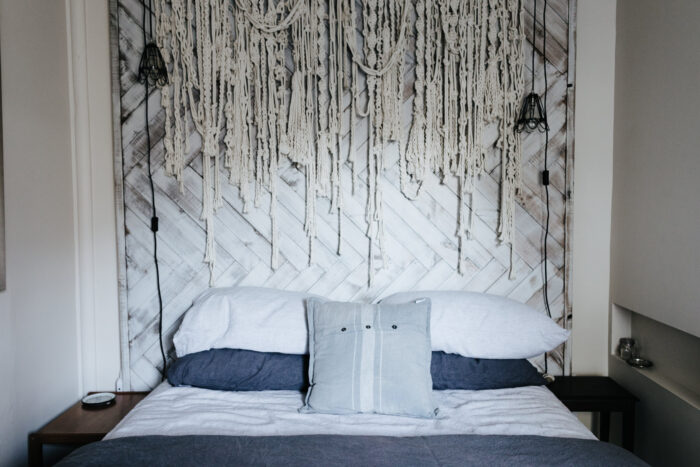 Bed with wooden head board and ropes hanging