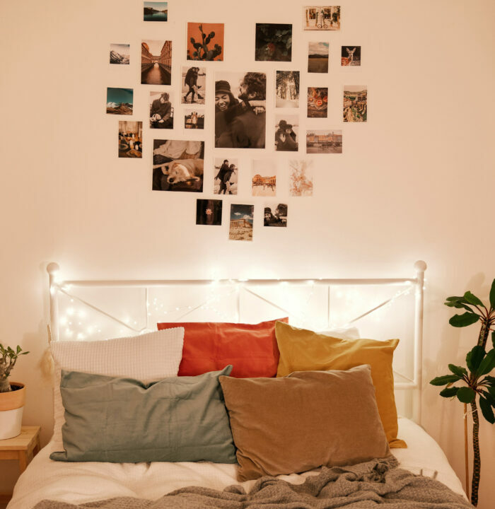 Bed with pillows near the wall with a heart shaped photo collage 