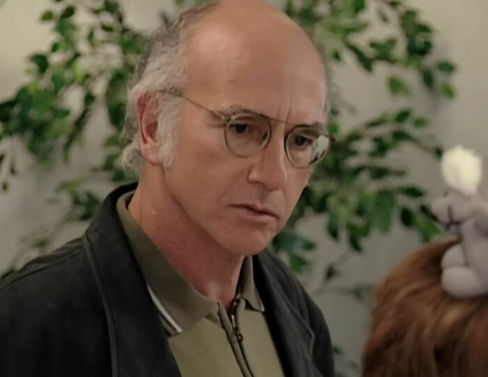Larry David standing near plant and looking from Curb Your Enthusiasm