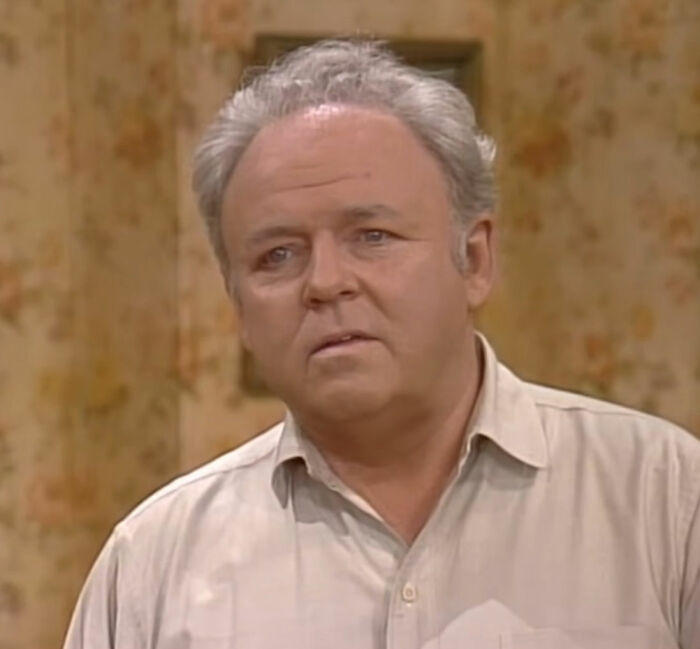 Archie wearing white shirt and looking from All in the Family