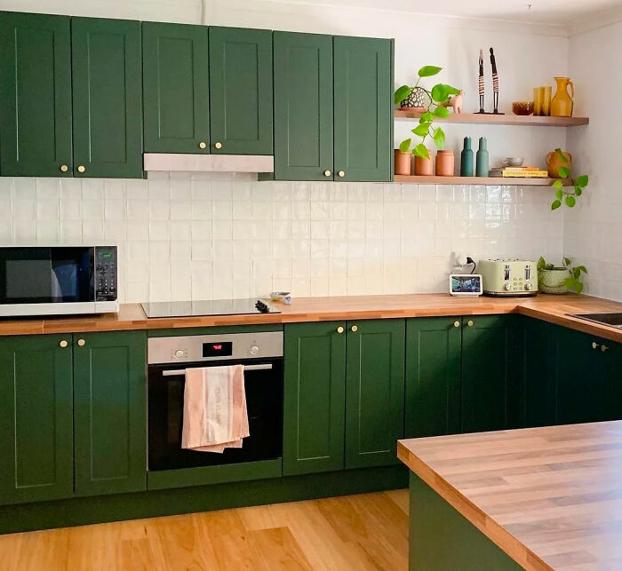Green kitchen with green cabinets and wooden shelves