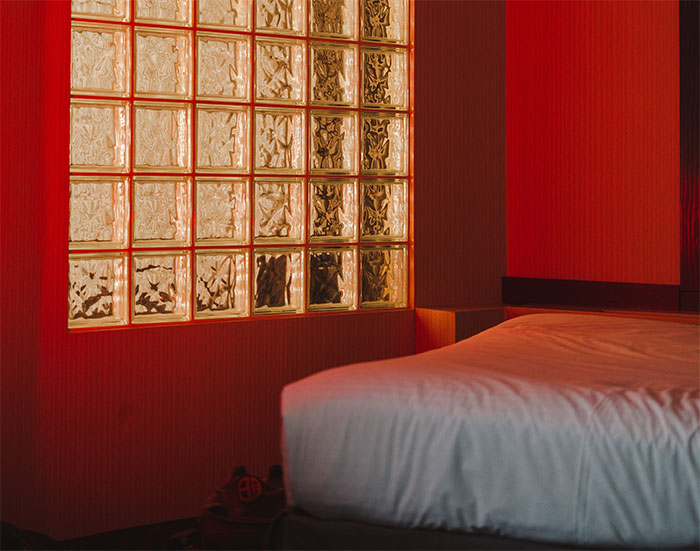 A dark red room with a bed and glass panels on a wall