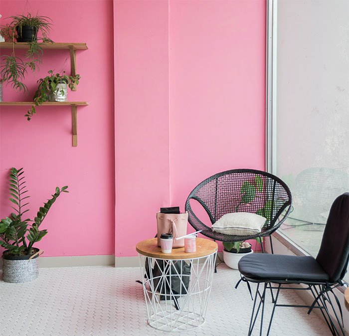 A bright pink room with a table and black chairs