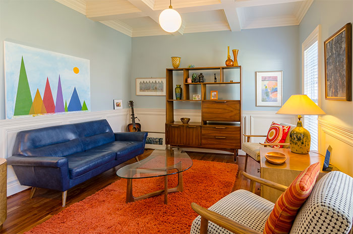 A light blue room with many colorful pieces of furniture