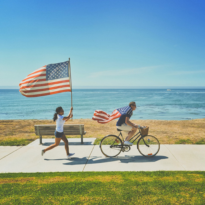 Man riding a bike, girl running with American flag 