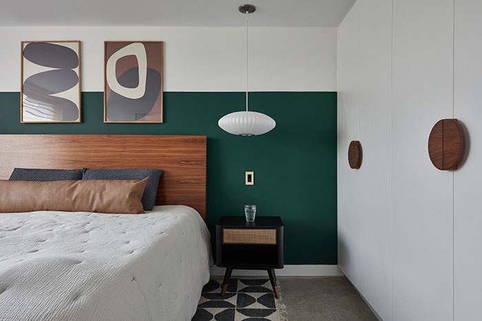Room with white and green walls with paintings and bed